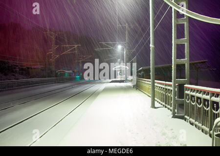 Notte perron. Nevicata sulla deserta stazione ferroviaria, umore di abbandono e di imprevedibilità (Solitudine). Pericolo per la ricezione di Hollywood film di criminalità Foto Stock