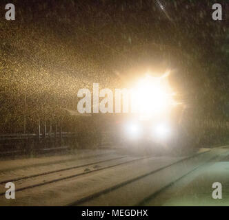 Sera treno arriva alla stazione. Nevicata complica il trasporto di passeggeri, blocchi di neve. Blizzard e derive di neve Foto Stock