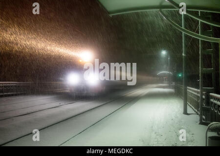 Sera treno arriva alla stazione. Nevicata complica il trasporto di passeggeri, blocchi di neve. Blizzard e derive di neve Foto Stock