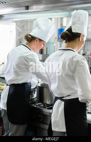 Femmina lavoro cuochi in cucina industriale Foto Stock