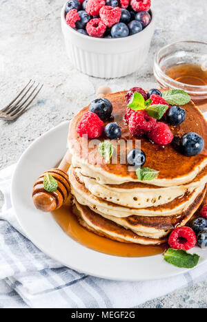 Una sana prima colazione estate,in casa classic american pancake con bacche fresche e miele, mattina pietra grigio chiaro sfondo spazio di copia Foto Stock