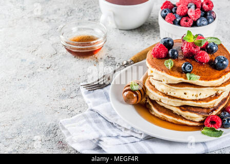 Una sana prima colazione estate,in casa classic american pancake con bacche fresche e miele, mattina pietra grigio chiaro sfondo spazio di copia Foto Stock