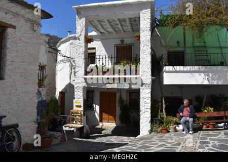 Uomo seduto su un banco di lavoro, Pampaneira village square, Pampaneira, Las Alpujarras, provincia di Granada, Spagna Foto Stock