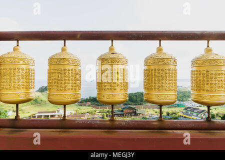 Cinque golden ruote della preghiera al tempio Sanbanggulsa con vista sulla costa, Sanbang-ro, Jeju Island, Corea del Sud Foto Stock