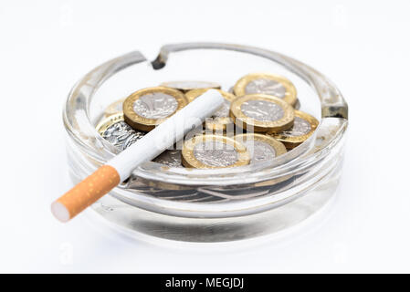 Sigarette e British Pound monete in un posacenere Foto Stock