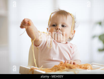 Piccolo bambino di mangiare il suo pranzo e facendo un pasticcio Foto Stock