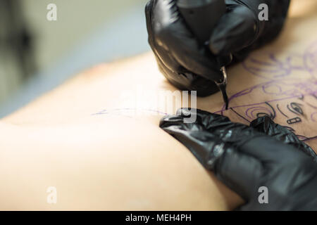 Tattooer che mostra il procedimento di preparazione di un tatuaggio, mani tenendo una macchina tatoo. Foto Stock