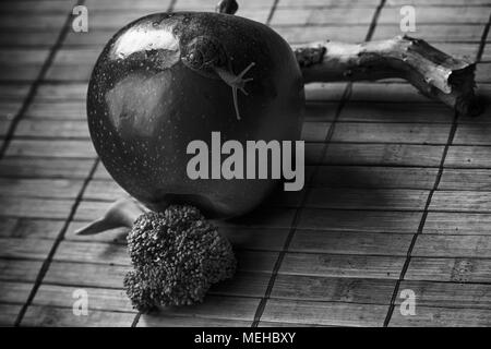 Seduta di lumaca su apple e il tronco di albero e andare a verde broccoli, legno di bambù, sullo sfondo di close-up di sfondo animale. Foto Stock