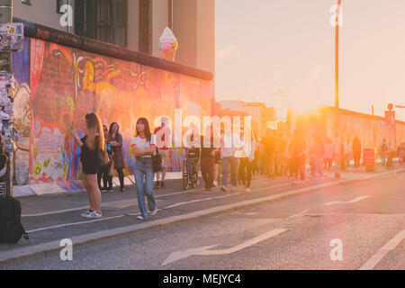 Berlino, Germania - Aprile 2018: i giovani a piedi a muro di Berlino ( East Side Gallery) sul giorno di estate serata con il cielo al tramonto Foto Stock