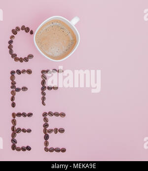Testo fatto di chicchi di caffè: caffè. La consistenza dei chicchi di caffè su un sfondo rosa. Puzzolente, saturo brown arabo i chicchi di caffè. Copia dello spazio. Foto Stock