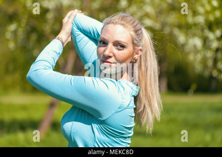 Giovane donna si allunga in un abito di sport Foto Stock