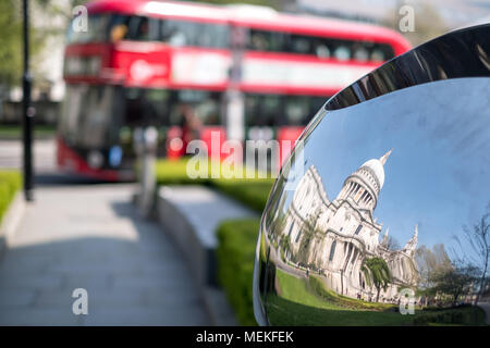 Immagine distorta della Cattedrale di St Paul, Londra UK, riflessa in metallo lucido la superficie della scultura a specchio, offuscata bus rosso in background. Foto Stock