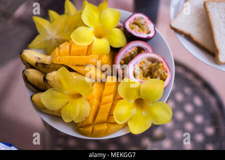 Mango, banana, frutto della passione ciotola guarnita con frutta fresca e fiori Foto Stock