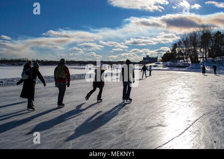 I pattinatori godendo una giornata soleggiata sul percorso di pattinaggio sul lago Ramsey, Sudbury, Ontario Foto Stock