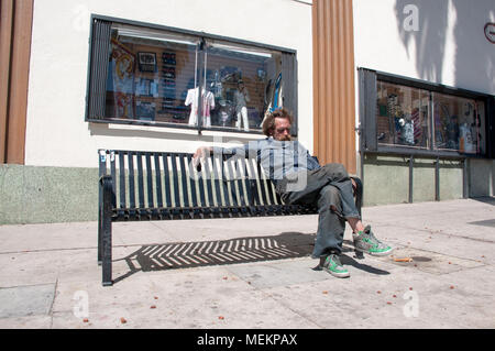 HOLLYWOOD - Aprile 01, 2018: uomo non identificato dormendo mentre seduta sul banco di strada nella città di Hollywood, CA. Foto Stock