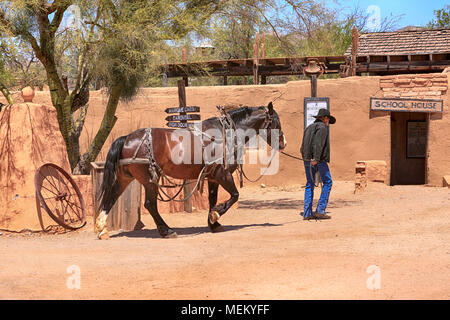 Il vecchio Cowboy portando il suo cavallo per la costruzione stabile presso la vecchia pellicola di Tucson Studios parco divertimenti in Arizona Foto Stock