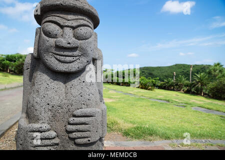 Dol Harubang statua nel verde di prati e alberi in background a Yongmeori Beach, Sanbang-ro, Jeju Island, Corea del Sud Foto Stock