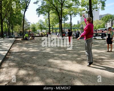 Persone a giocare a bocce in ombra lungo il canale su un caldo, aprile pomeriggio.Bassin de la Villette di Parigi, Francia. Foto Stock