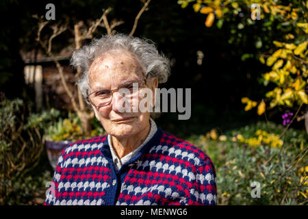 Donna anziana seduta nel suo giardino nel West Sussex England Foto Stock