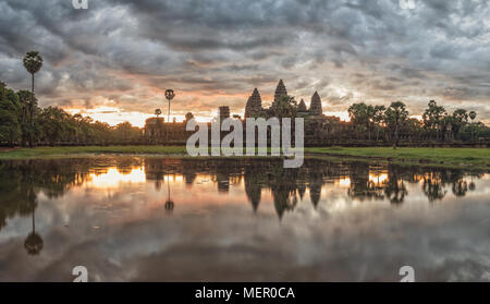 Cambogia antico tempio complesso Angkor Wat a sunrise con drammatica nuvole sopra le torri e la riflessione in Stagno. Famosa destinazione di viaggio. Foto Stock