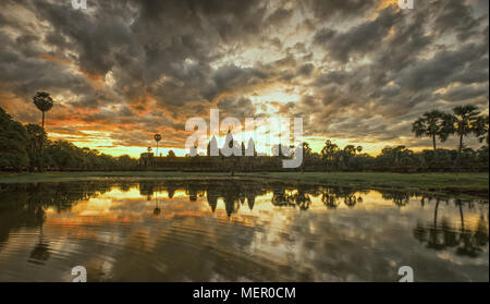 Cambogia antico tempio complesso Angkor Wat a sunrise con drammatica nuvole sopra le torri e la riflessione in Stagno. Famosa destinazione di viaggio. Foto Stock