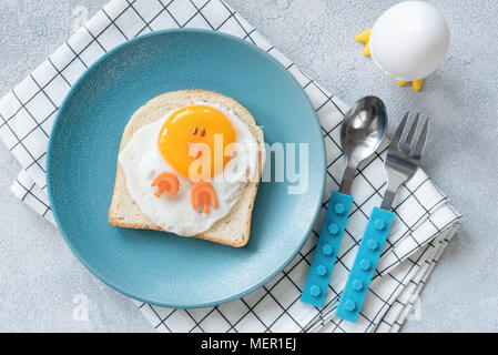 Uovo divertente brindisi per bambini sulla piastra blu, vista dall'alto. A forma di pollo sandwich, cibo arte. Foto Stock