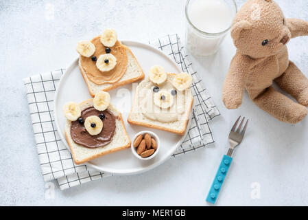 Funny arte cibo colazione toast per bambini. Orsacchiotto di peluche dado burro toast su bianco, vista dall'alto Foto Stock