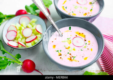 Rosa rafano freddo zuppa di cetriolo e yogurt guarnita con peperoncino secco, pepe, prezzemolo, olio d'oliva e crudites servita in ciotole Foto Stock