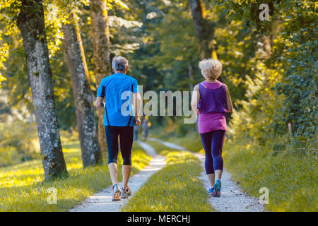 Lunghezza piena vista posteriore di una coppia senior jogging insieme all'aperto Foto Stock