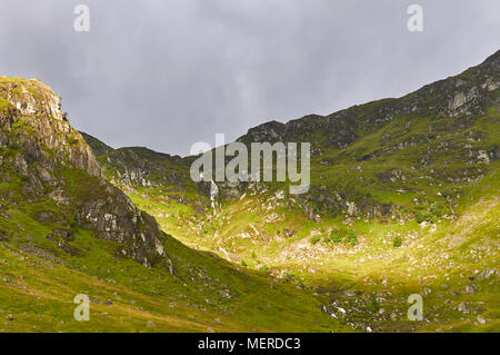 La luce del sole sui fianchi ripidi della tassa Corrie, di origine glaciale Corrie nel cuore di Angus Glens, parte del Cairngorm National Park in Scozia Angus. Foto Stock