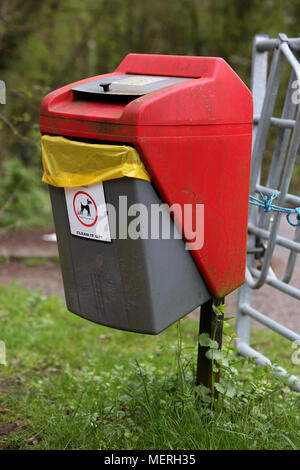 Un rosso brillante e Grey Dog Poo bin in Southwater Country Park, Horsham, Regno Unito. Foto Stock