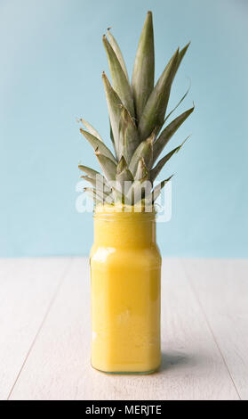 Un bicchiere pieno di ananas sano frullato di frutta succo o decorata con la testa di foglia di ananas Foto Stock
