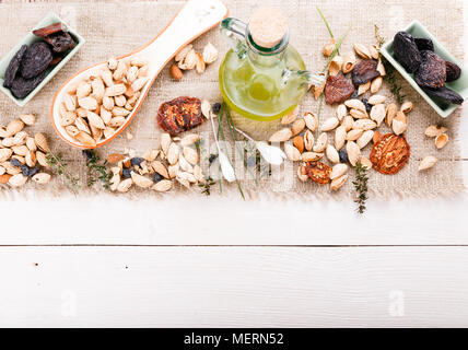 Alimenti biologici amonds, uva passa, albicocche secche, pomodori secchi, prugne, frutta secca, olio d'oliva nella ciotola di legno. Mix di cibo sfondo, vista dall'alto, piana, laici Foto Stock
