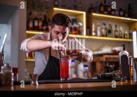 Barista decorare non alcoliche cocktail di melograno con fettine di lime Foto Stock