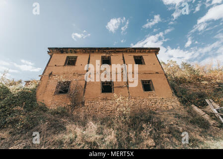 Abbandonato danneggiato vecchia casa contro blu cielo molto nuvoloso Foto Stock