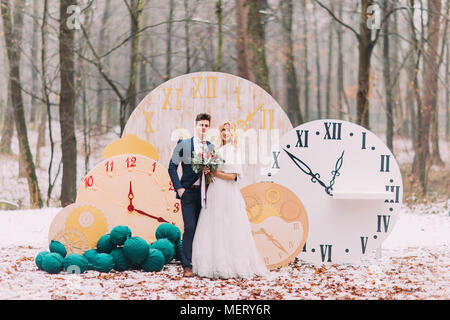 Happy sposi in posa a grandi orologi vintage in autunno foresta. Decorazioni Creative Foto Stock