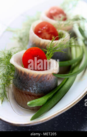 Il Filetto di aringa in olio. Rotoli con aneto , cipolla verde e pomodori ciliegia . Foto Stock