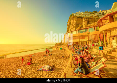 Azenhas do Mar, Portogallo - 5 Agosto 2017: i turisti a prendere il sole e rilassarsi sulla famosa spiaggia di Azenhas do Mar a Colares, Costa Atlantica, con la sua piscina naturale visibile con la bassa marea. La luce del sole al tramonto. Foto Stock