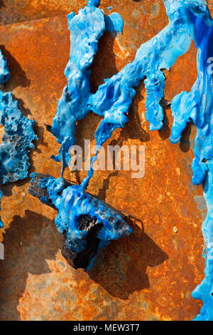 Blu in plastica fusa è una copertura arrugginito metallo in foglio su un bruciato cumulo di rifiuti Foto Stock