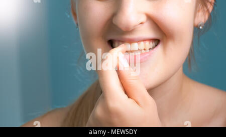 Primo piano immagine della giovane donna tenendo fuori il cibo bloccato da denti Foto Stock