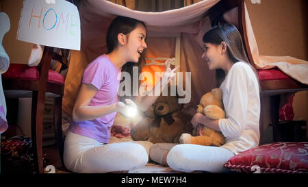 Due ragazze sorridenti giocando in tepee tenda in camera da letto e raccontare storie Foto Stock