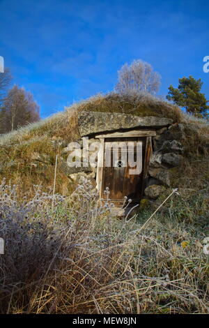 Porta di legno ad una radice tradizionale cantina usata per immagazzinare le scorte di cibo a bassa temperatura e umidità costante su un gelido autunno mattina in Svezia. Foto Stock