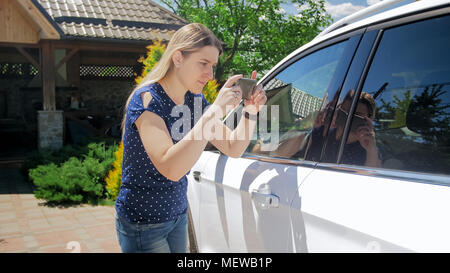 Femmina giovane conducente di scattare le foto della sua auto per la vendita on-line Foto Stock