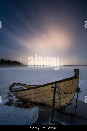 Scenario tenebrologo con la barca di legno e moody atmosfera a notte invernale in Finlandia Foto Stock