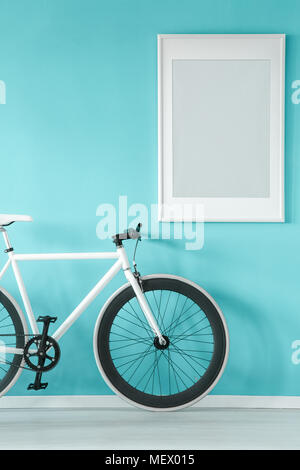 Grigio poster sul pastello blu parete in anticamera interno con bicicletta bianchi Foto Stock