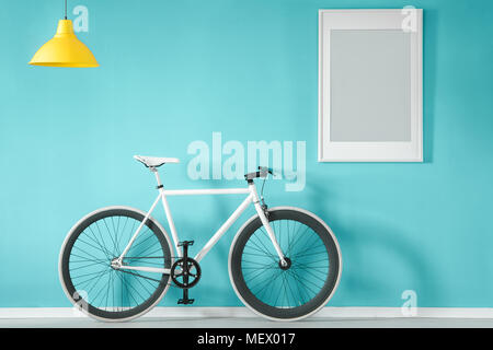 Bike bianco contro la parete blu con il grigio poster in salotto interno con luce gialla Foto Stock