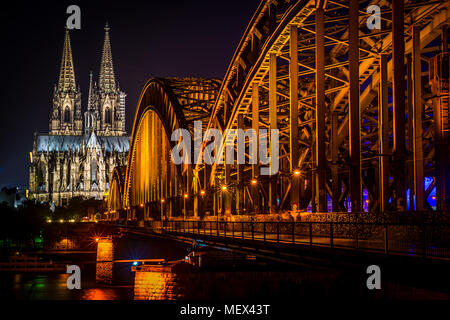 Le ore notturne al ponte di Hohenzollern con la cattedrale di Colonia a Colonia, in Germania. Foto Stock