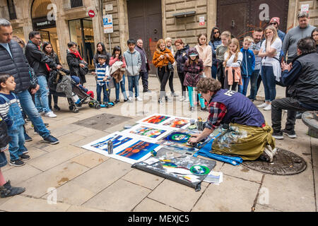 Un uomo crea un oggetto grafico utilizzando vernice spray su carta in strada come una dimostrazione per il passaggio di turisti. Foto Stock