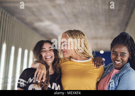 Ridere del gruppo di giovani amici di sesso femminile avente divertimento mentre camminare insieme verso il basso una passerella nella città di notte Foto Stock