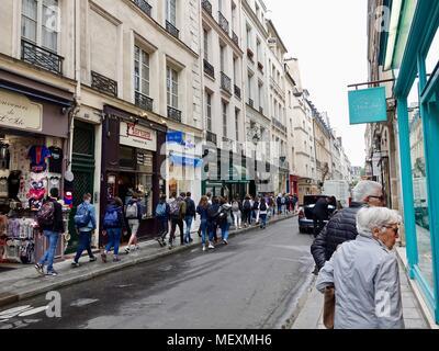 Coppia di anziani negozi di vetro, classe di alta scuola gli studenti in gita passeggiate lungo il lato opposto della strada. Rue Saint-Louis en L'Ile. Parigi Foto Stock